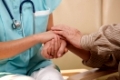 Closeup of joined hands of nurse and elderly patient. 